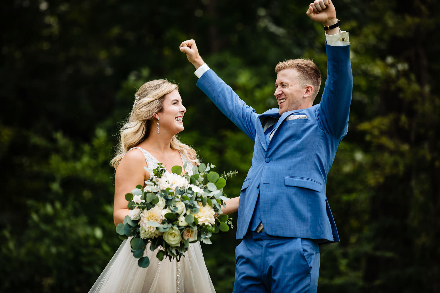 A groom standing next to his bride cheering on his wedding day