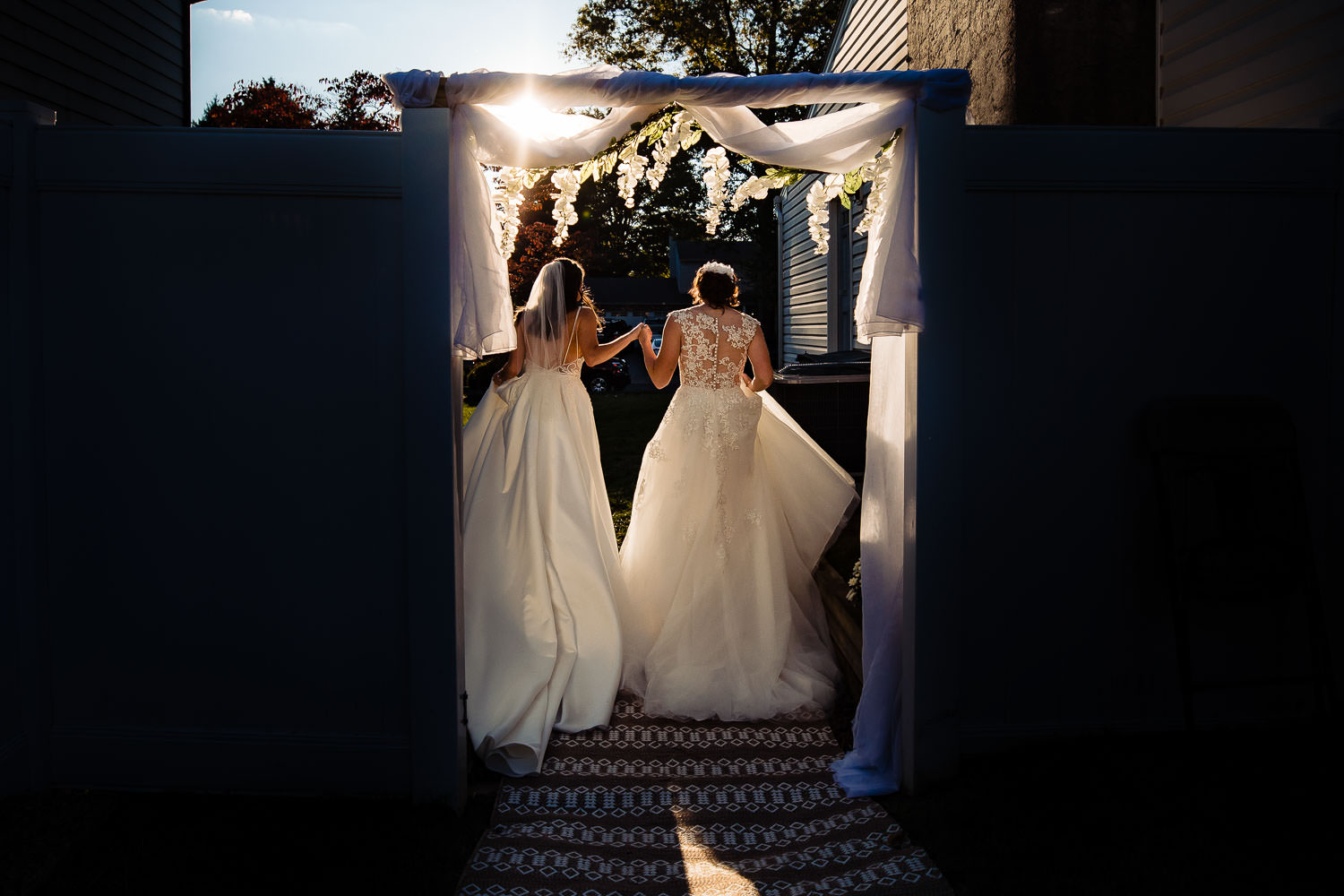 Two brides holding hands under a bridal arch